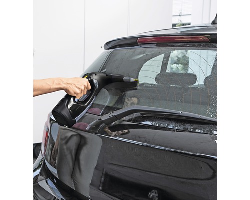 Een persoon reinigt de achterruit van een auto met een ruitenreiniger.