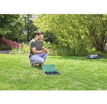 Man bedient irrigatiebesturing met smartphone in de tuin