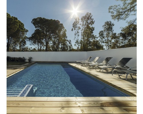 Buitenzwembad met houten terras en ligstoelen voor bomen
