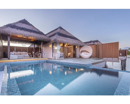 Uitzicht op een bungalow met rieten dak en zwembad