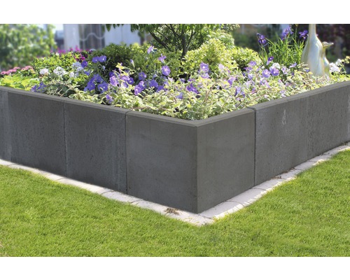 Verhoogde tuinbak van betonstenen beplant met bloemen in de tuin