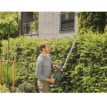 Man snoeit heg met een heggenschaar in de tuin.