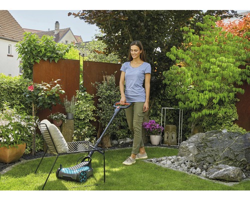 Vrouw maait gazon met een grasmaaier in de tuin.
