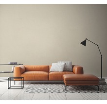 Woonkamer met leren bank, hocker, staande lamp en tapijt op houten vloer