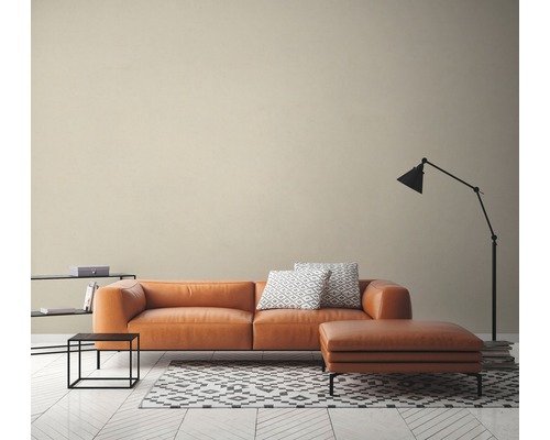 Woonkamer met leren bank, hocker, staande lamp en tapijt op houten vloer