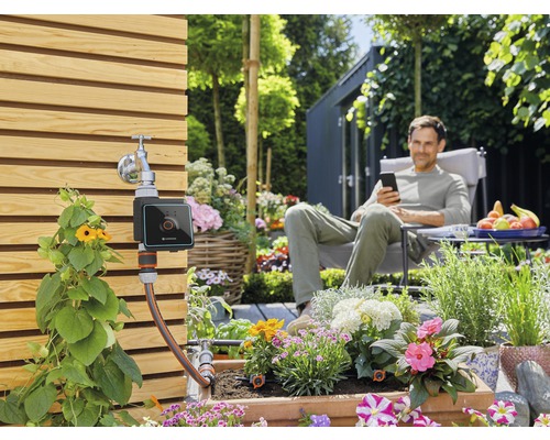 Tuinbewateringssysteem met digitale besturing en ontspannen man op de achtergrond