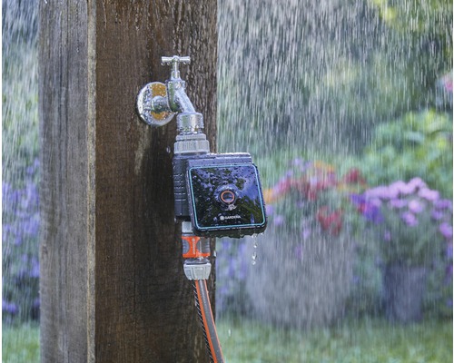 Gardena waterkraan met irrigatiecomputer en aangesloten tuinslang in de regen