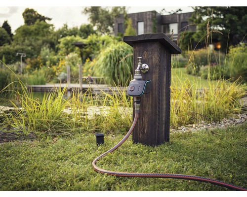 Irrigatiebediening met kraan en slang in de tuin