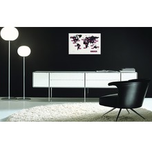 Interieur met twee staande lampen, een dressoir, een fauteuil en een wereldkaart aan de muur.