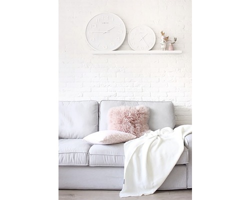 Woonkamer met bank, kussens, deken en twee klokken aan de muur