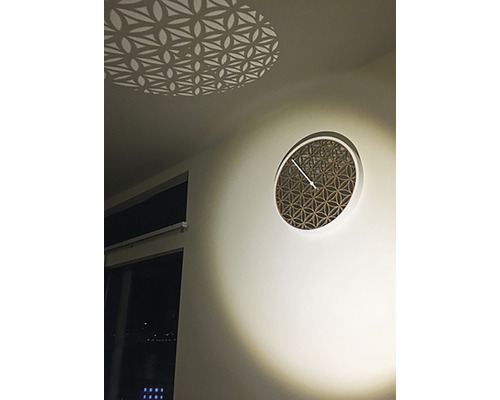 Decoratieve wandklok met geometrisch patroon en lichteffect op het plafond