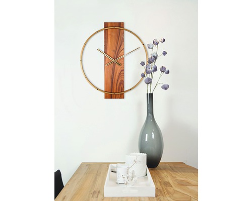 Wandklok met houten details en gouden accenten boven een houten tafel met decoraties.