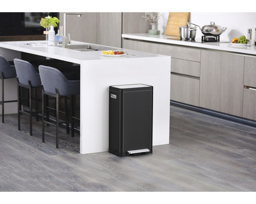 Zwarte afvalemmer met pedaal in een moderne keuken met kookeiland en barkrukken