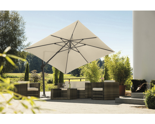 Vierkante zweefparasol boven rotan zithoek in de tuin