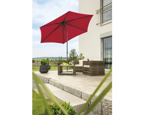Terras met rode parasol en tuinmeubelen van rotan.