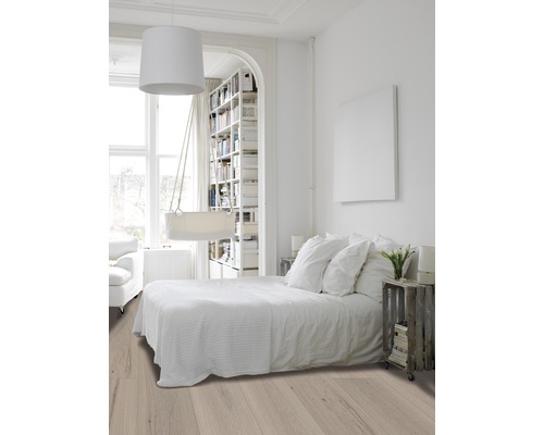 Lichte, vriendelijke slaapkamer met houten vloer, bed en boekenkast