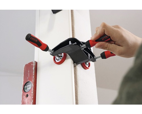 Iemand fixeert een werkstuk met een hoekklem van Bessey.