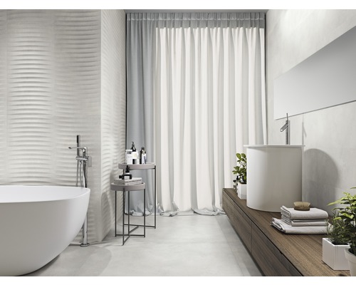 Badkamer met ligbad, wastafel en gestructureerde wandtegels