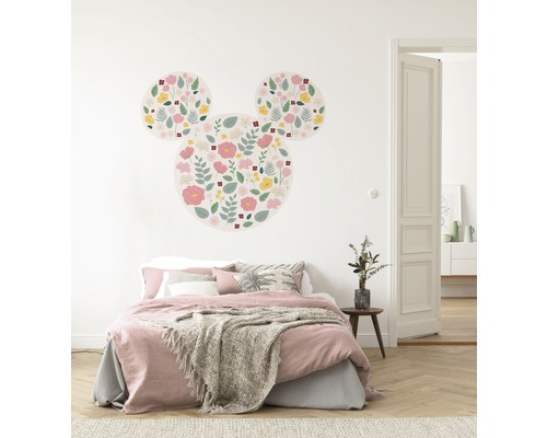 Decoratieve kinderkamer met muursticker in de vorm van een Mickey Mouse met bloemmotief boven een bed.