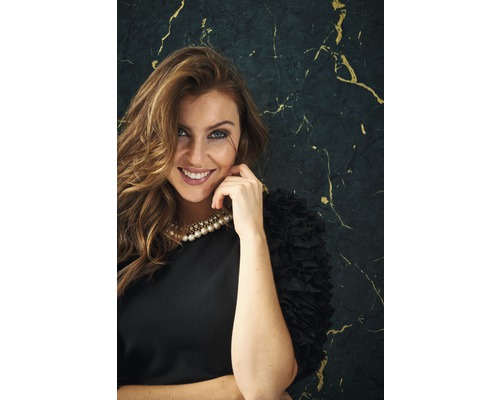 Portret van een lachende vrouw met een parelketting en een zwarte jurk