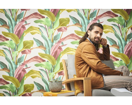 Een kamer met een tropisch bladerbehang en een persoon die op een stoel zit