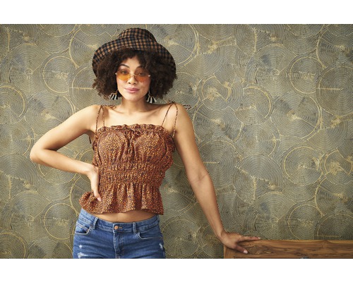 Vrouw met hoed, top met patroon en jeans voor een behang met patroon