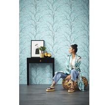 Kameroverzicht met patroonbehang met boommotief, console, decoratie en zittende persoon