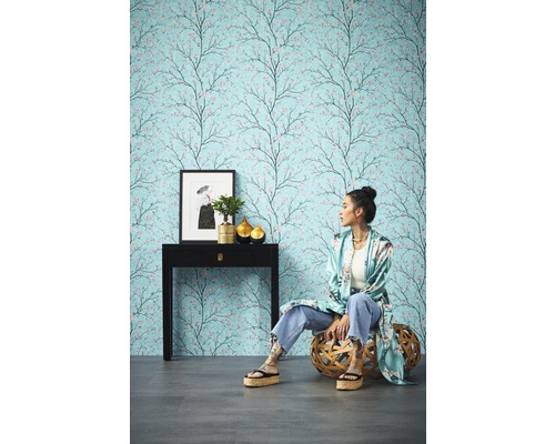 Kameroverzicht met patroonbehang met boommotief, console, decoratie en zittende persoon