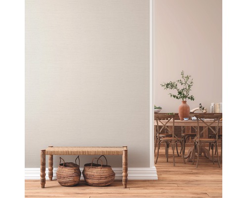 Woonkamer met textielbehang, houten vloer, zitbank en eetgedeelte op de achtergrond.