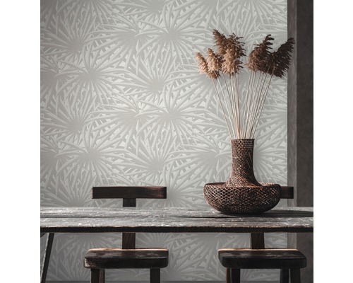 Een kamer met een patroonbehang, een houten tafel en een mand met sierplanten.