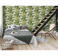 Slaapkamer met een wandbekleding met plantmotieven, bed, trap en een stoel.