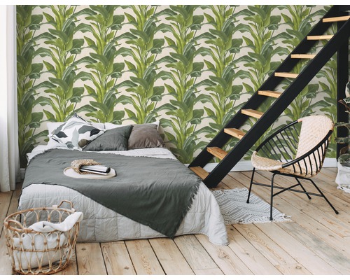 Slaapkamer met een wandbekleding met plantmotieven, bed, trap en een stoel.
