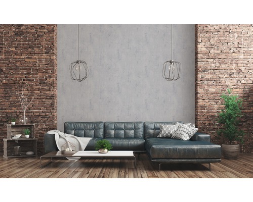 Woonkamer met leren bank, salontafel, rekken, kamerplanten en bakstenen muur