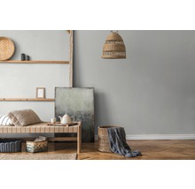Woonkamer met houten stellingkast, rieten meubels, textiel en abstract schilderij