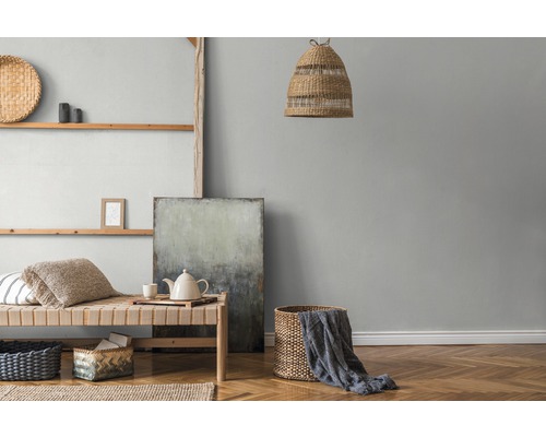 Woonkamer met houten stellingkast, rieten meubels, textiel en abstract schilderij