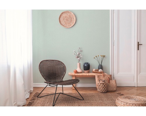 Woonkamer met rotan meubels en een licht wanddesign voor een vriendelijke sfeer.