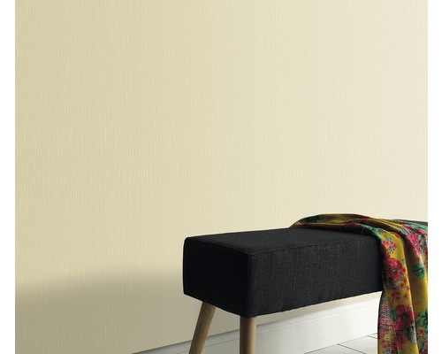 Licht behang met fijne structuur naast een bank met doek