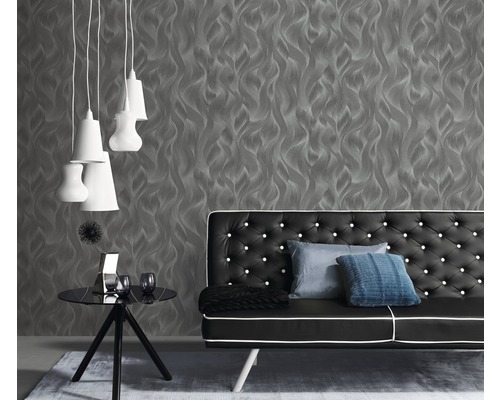 Woonkamer met grijs behang, zwarte bank en witte lampen