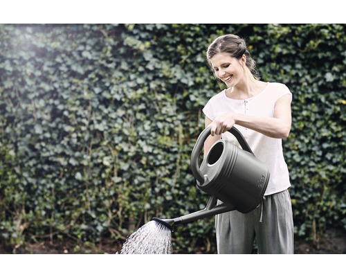 Vrouw geeft planten water met een gieter in de tuin