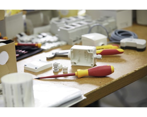 Opname van installatiemateriaal zoals lasdoos, schroevendraaier en kabelwartels op een tafel.