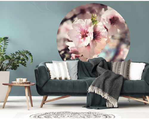 Woonkamer met bank, kussens, dekens, tafel, plant en muursticker met bloemmotief