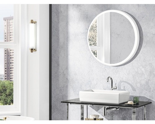 Badkamer met ronde spiegel, waskom en wandlamp.