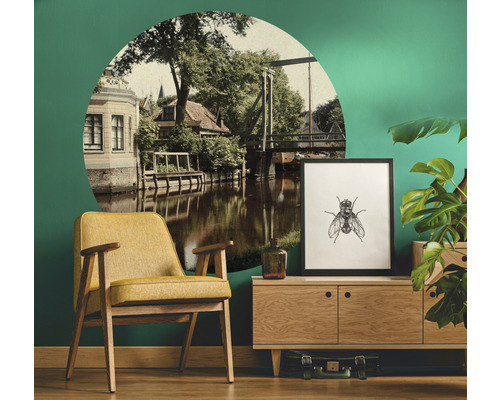 Woonkamer met fauteuil, dressoir, kamerplant, decoratie en muursticker met rivierlandschap