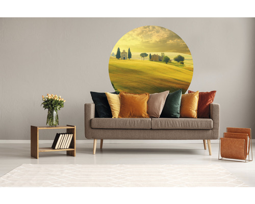 Woonkamer met grijze bank, kussens in verschillende kleuren, muursticker met landschap, houten tafel met vaas en tijdschriftenrek