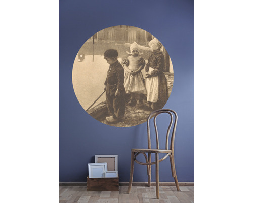 Wanddecoratie met muursticker kinderen en houten stoel naast houten kist met fotolijsten