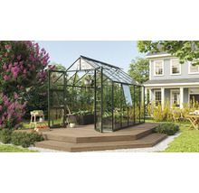Kas op een houten terras in een tuin met planten en een woonhuis.