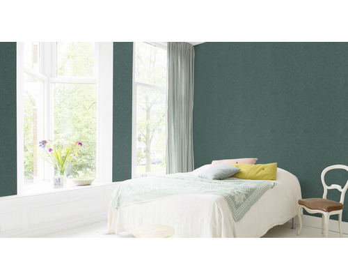 Slaapkamer met groene vliesbehang, bed, raam en stoel.