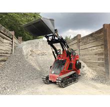 Rode minilader met schep voor een stapel grind