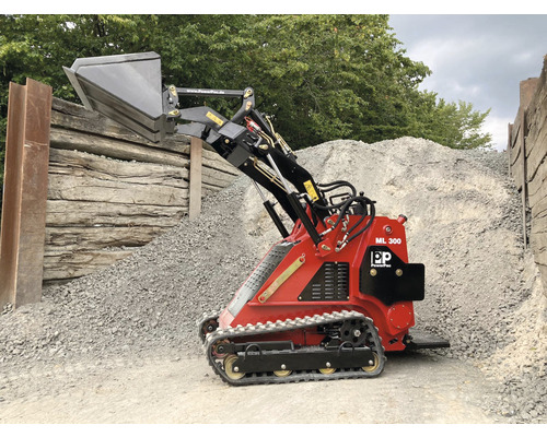 Compacte rode minilader met schep voor een berg grind.