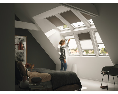 Vrouw bedient dakraamrolluiken in de slaapkamer